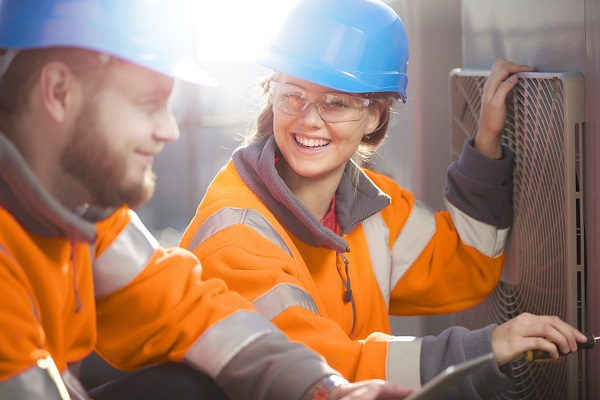 Teen girl in hard hat working with man
